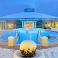 Ein Spa-Becken der Driburger Therme ist umgeben von Schnee, unter einem beleuchteten Winterhimmel.