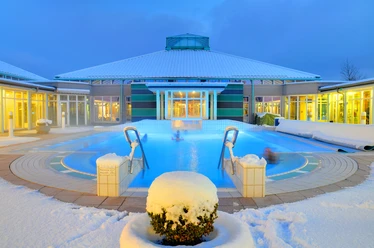 Driburger Therme im Winter Ein Spa-Becken der Driburger Therme ist umgeben von Schnee, unter einem beleuchteten Winterhimmel.