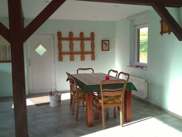 Esszimmer mit Holztisch und Stühlen vor einem Fenster. Geometrische Holzdekorationen an den Wänden.