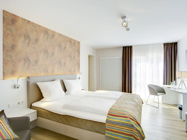 Komfort- und Superiorzimmer Helles Superiorzimmer mit modernen Annehmlichkeiten, großem Bett, Schreibtisch und Balkonzugang.