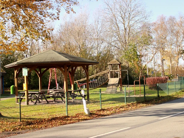 Grillplatz u. Spielplatz Oberndorf Bentwisch Überdachter Grillplatz mit Sitzbänken und Spielturm hinter Zaun in Oberndorf-Bentwisch.