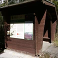 Schutzhütte mit Infotafel Hölzerne Schutzhütte im Wald mit Infotafel zur Schildburg, umgeben von Bäumen und Sonnenlicht.