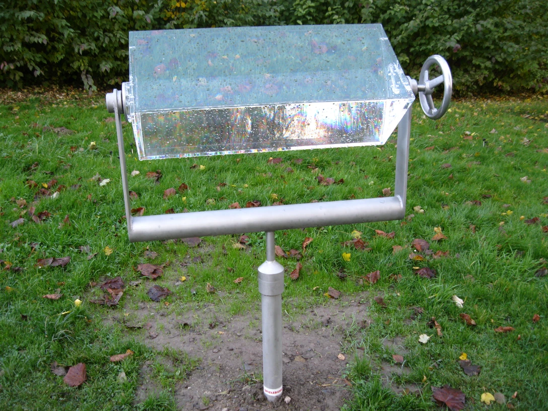 Wasserprisma in Extertal-Laßbruch Prismaförmiges Wasserspiel in einem Park, montiert auf einer Metallstange mit drehbarem Handrad.