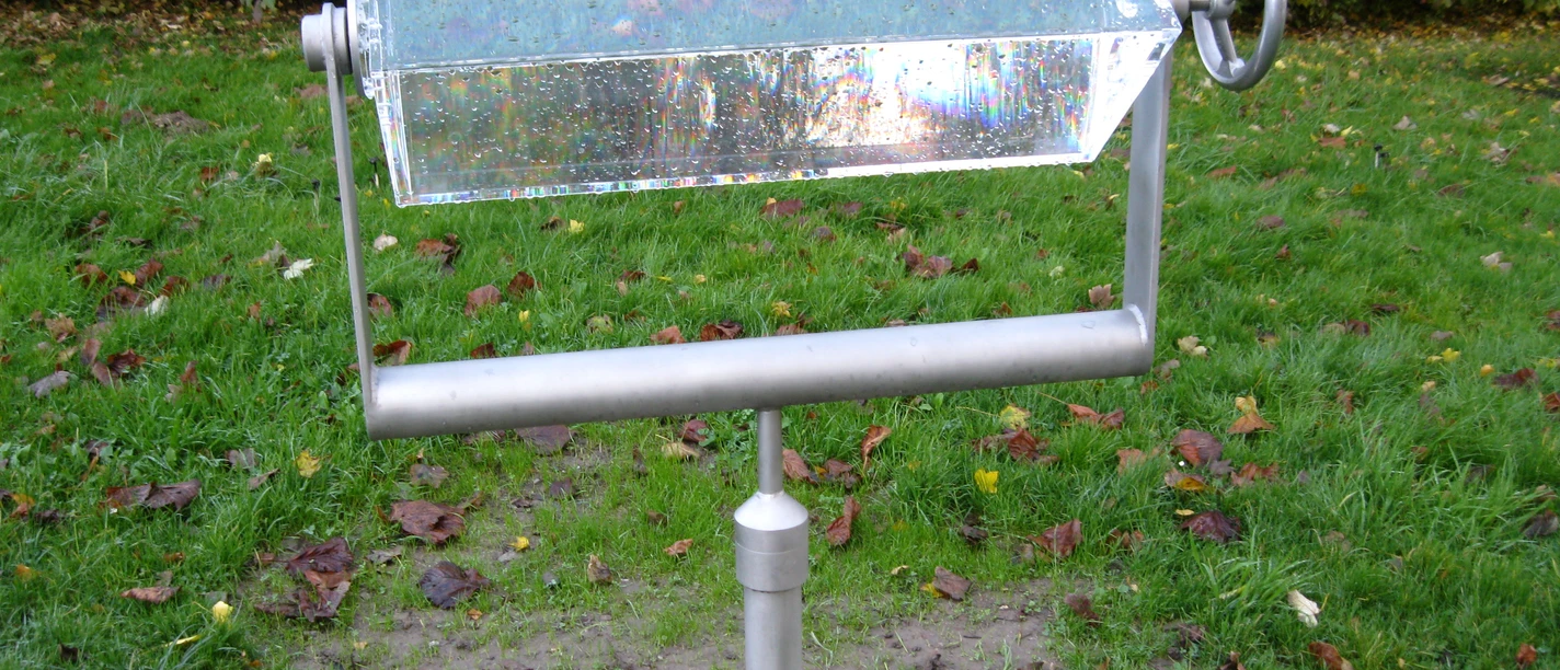 Wasserprisma in Extertal-Laßbruch Prismaförmiges Wasserspiel in einem Park, montiert auf einer Metallstange mit drehbarem Handrad.