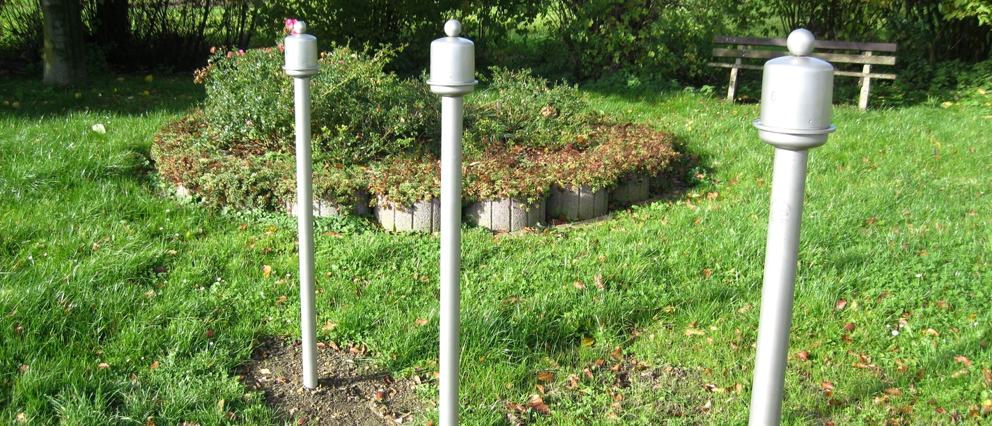 Duftorgel in Extertal-Kükenbruch Drei weiße Duftstelen im Grünen, umgeben von Büschen und Bäumen, nahe einer Holzbank im Park.