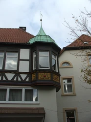 Hirsch-Apotheke Fachwerkgebäude mit Erker und grünem Kupferdach vor bewölktem Himmel, rechts angrenzendes Gebäude.