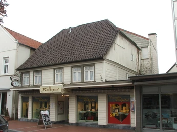 Lange Straße 89 Historisches Fachwerkhaus mit Uhr an der Fassade, darunter ein Juwelier-Geschäft in einer Einkaufsstraße.