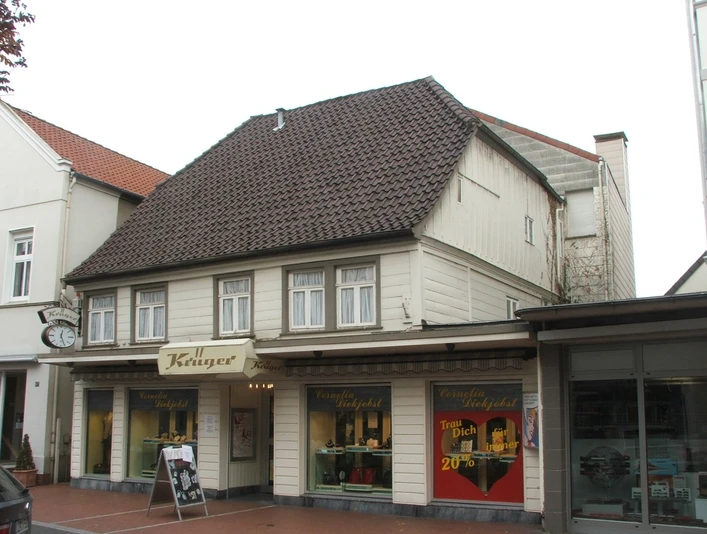 Lange Straße 89 Historisches Fachwerkhaus mit Uhr an der Fassade, darunter ein Juwelier-Geschäft in einer Einkaufsstraße.