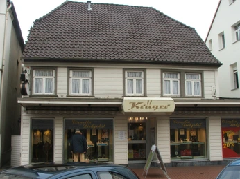 Lange Straße 89 Zweistöckiges Fachwerkhaus mit Satteldach, Schaufenstern und zentralem Eingang in einer Fußgängerzone.