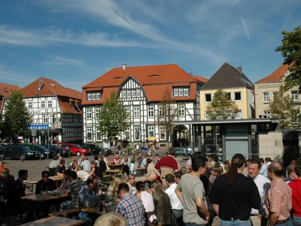 Neustadtmarktplatz Menschen versammeln sich auf einem belebten Marktplatz mit Fachwerkhäusern und Tischen unter freiem Himmel.