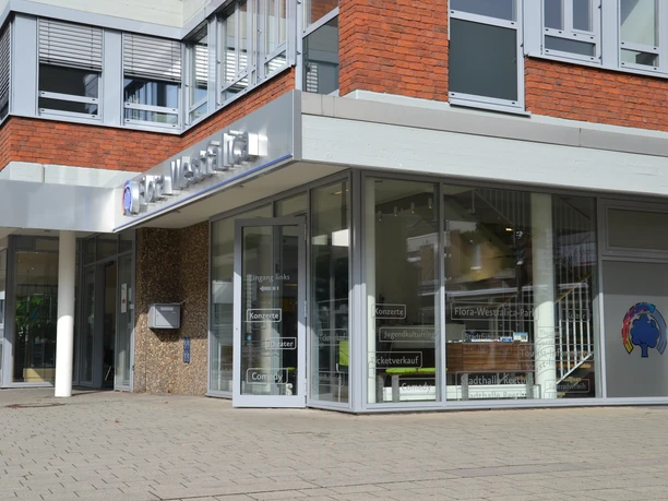 Flora Westfalica GmbH Eckansicht eines modernen Gebäudes mit Glasfassaden und Schildern, das Erdgeschoss zeigt Firmennamen.