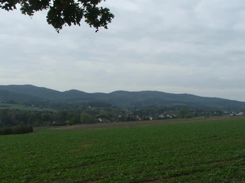 Blick auf Hörste Weite Felder und sanfte Hügel unter wolkigem Himmel, mit vereinzelten Dörfern in der Ferne.