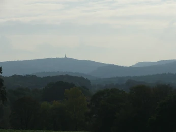 Blick zum Hermannsdenkmal Hügelige Landschaft mit dichtem Wald, im Hintergrund ein Monument auf einem entfernten Bergkamm.