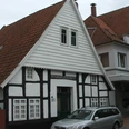 Fachwerkhaus Rhienstraße 43 Fachwerkhaus mit weißem Giebel und dunklen Holzbalken, davor ein geparktes silbernes Auto.
