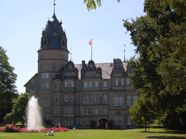 Fürstliches Residenzschloss Fürstliches Residenzschloss mit markantem Rundturm, umgeben von gepflegtem Garten und Springbrunnen.