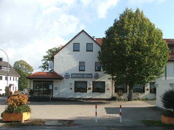 Gebäude mit weißer Fassade, dem Schriftzug "Hörster Krug" und seitlichem Zugang mit Rampe.