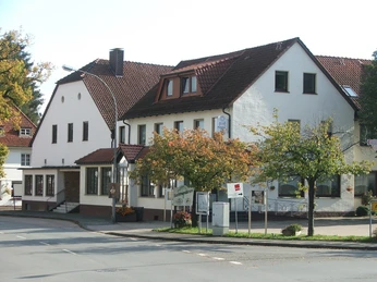 Historisches Gasthaus Hörster Krug mit weißen Fassaden und rotem Ziegeldach an einer Straßenecke.