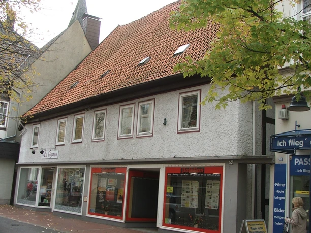 Das Gebäude mit rotem Ziegeldach beherbergt ein Fotofachgeschäft und liegt in einer belebten Straße.