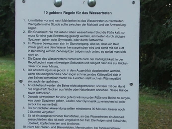 Hinweisschild im Freien mit Ratschlägen für die korrekte Anwendung eines Wassertretbeckens.
