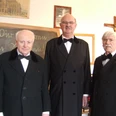 Dorfschullehrer im Dorfschulmuseum Drei ältere Herren in schwarzen Anzügen im Dorfschulmuseum vor einer Schultafel.