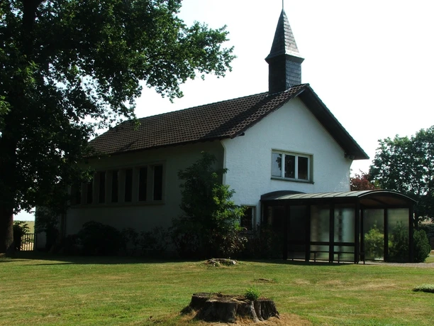 Friedhofskapelle Heiden Friedhofskapelle Heiden mit dunklem Dach und kleinem Turm, umgeben von grünen Bäumen und Wiesen.