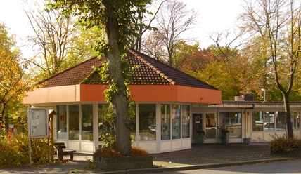Tourist Information Bad Driburg, rundes Gebäude mit großen Fenstern, umgeben von herbstlichen Bäumen.