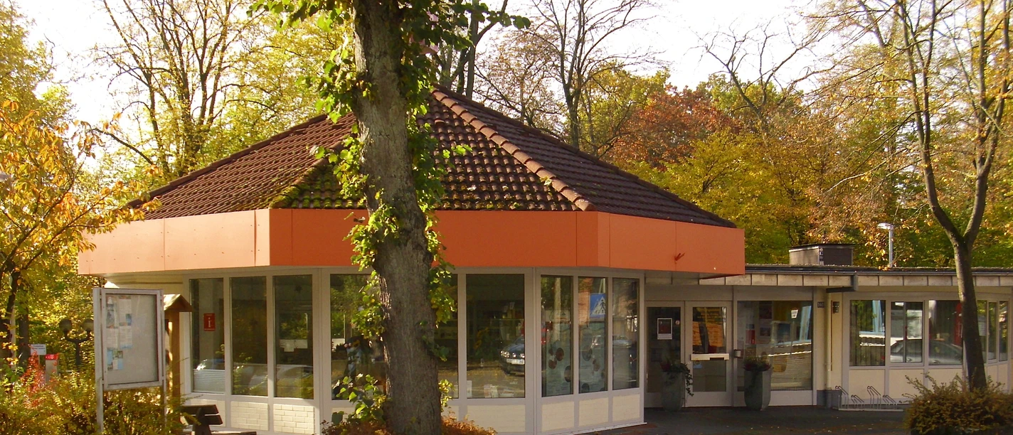 Tourist Information Bad Driburg, rundes Gebäude mit großen Fenstern, umgeben von herbstlichen Bäumen.