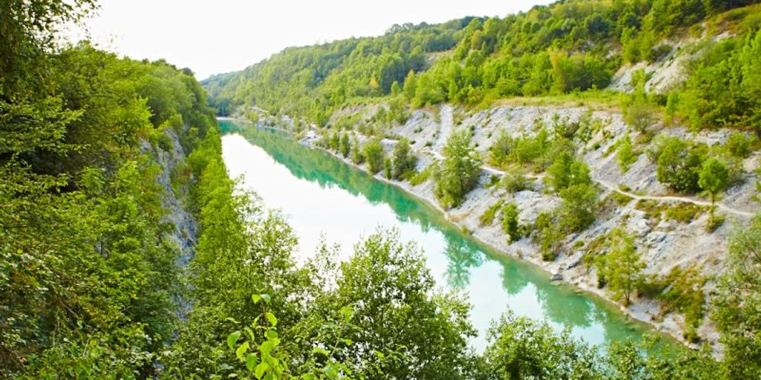 Lengericher Canyon Smaragdgrüner See eingerahmt von bewaldeten Klippen, umgeben von üppiger Vegetation.