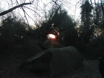 Sonnenaufgang hinter den Johannissteinen im Winter, Bewuchs umrahmt den goldenen Lichtschein.