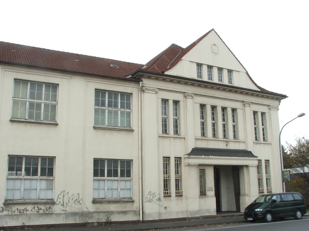 Ein historisches, dreigeschossiges Gebäude mit graffitiverziertem Erdgeschoss und rotem Ziegeldach.