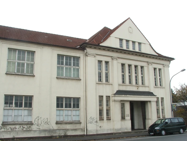 Ein historisches, dreigeschossiges Gebäude mit graffitiverziertem Erdgeschoss und rotem Ziegeldach.