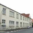 Friedrich-Ebert-Straße 4 Zweistöckiges Gebäude mit altertümlicher Fassade, Graffiti an den Wänden und parkenden Autos davor.