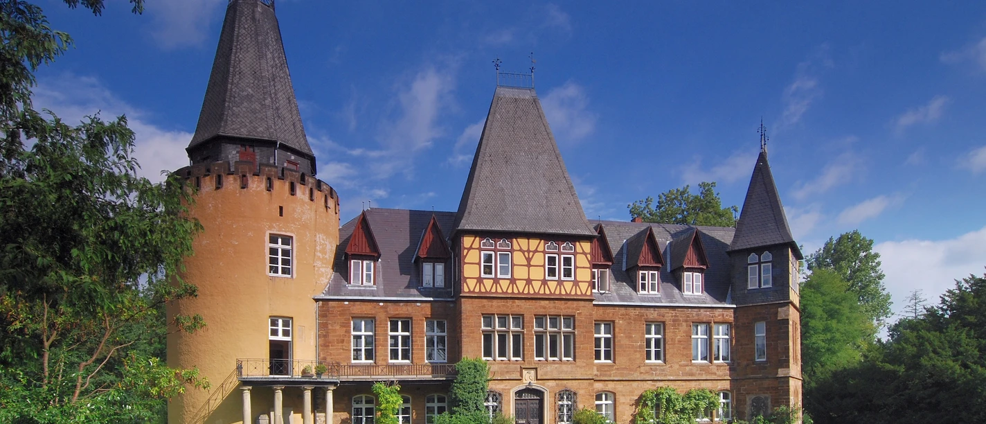 Schloss Hollwinkel Schloss Hollwinkel mit markanten Türmen und Fachwerkgebäude umgeben von gepflegter Grünanlage.