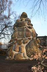 Ein pyramidenförmiges Denkmal aus großen, unregelmäßigen Feldsteinen, umgeben von kahlen Bäumen.