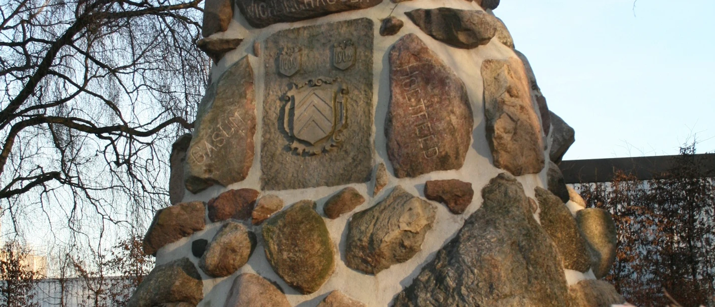 Ein pyramidenförmiges Denkmal aus großen, unregelmäßigen Feldsteinen, umgeben von kahlen Bäumen.