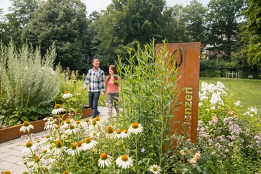 Kräuterbeete im Kurpark Bad Wünnenberg Zwei Personen spazieren durch eine gepflegte Gartenanlage mit vielfältigen Kräuter- und Blumenbeeten.