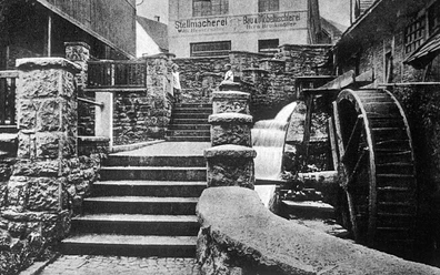 Historische Aufnahme der Mühlenpforte um 1910 mit Wasserrad und steinernen Treppenstufen.
