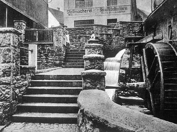 Mühlenpforte um 1910 Historische Aufnahme der Mühlenpforte um 1910 mit Wasserrad und steinernen Treppenstufen.