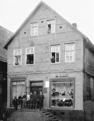 Haus Schiff Historisches Fachwerkhaus mit Menschen an Fenstern und Eingang, Schaufenster mit Hüten und Waren.
