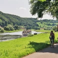 Am Dampferanleger Wehrden Blick vom Weser-Radweg auf den Dampferanleger in Wehrden, an dem ein Weserschiff anlegt, im Vordergrund zwei Radfahrer