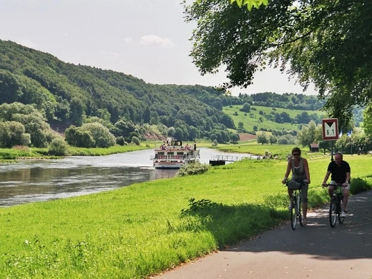 Am Dampferanleger Wehrden Blick vom Weser-Radweg auf den Dampferanleger in Wehrden, an dem ein Weserschiff anlegt, im Vordergrund zwei Radfahrer