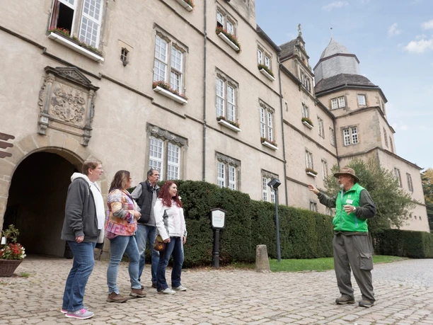 Vor dem Torbogen Schloss Varenholz Gruppe von fünf Personen mit einem Führer vor dem historischen Torbogen von Schloss Varenholz.