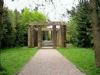 Ehrenmal Ehrenmal aus Stein mit massiven Säulen, eingebettet in einen bewaldeten Park, von Bäumen flankiert.