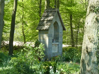 Steinkapelle im Wald bei Borchen-Dörenhagen umgeben von Frühjahrsblumen und lichten Bäumen.