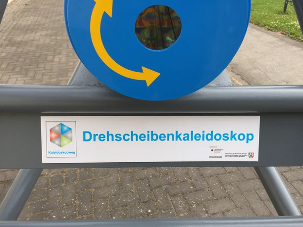 Drehscheibenkaleidoskop am Kaleidoskopweg Nahaufnahme vom Schild des Drehscheibenkaleidoskops.