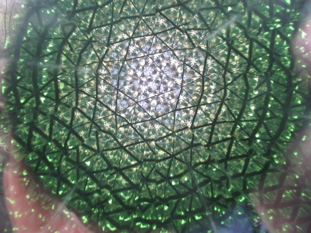 Hier sieht man sich selbst vielfach fragmentiert (in diesem Fall die Kamera) Kaleidoskopische Ansicht: Die Kamera fängt ein vielfach reflektiertes, grünes geometrisches Muster ein.