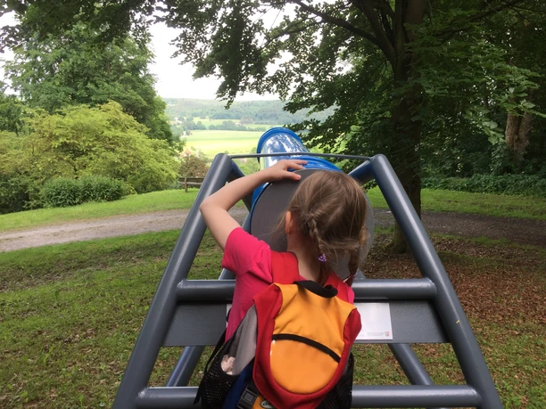 Mädchen guckt ins Kaleidoskop wo bunte Farbscheiben immer wieder neue Bilder entstehen lassen.