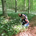Zwei Frauen betrachten blühenden Bärlauch auf einem Waldweg im Naturerbe-Wald bei Altenbeken.