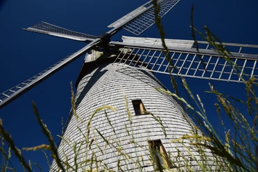 Windmühle Bavenhausen Historische Windmühle Bavenhausen mit hölzernen Flügeln, aus niedriger Perspektive vor blauem Himmel.