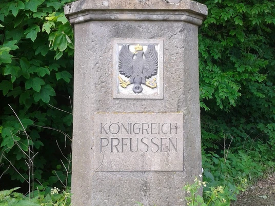 Hoheitsstein in Harzberg Steinerner Hoheitsstein in Harzberg mit preußischem Adler, umgeben von dichter Vegetation.